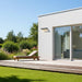 Modern house exterior with a deck, lounge chair, and garden.
