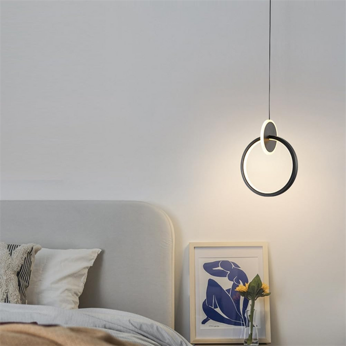 Modern pendant light hanging above a bed in a bedroom setting.