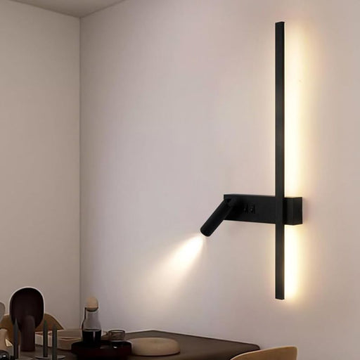 Modern wall-mounted light fixture on a neutral wall with a dining area in the background.