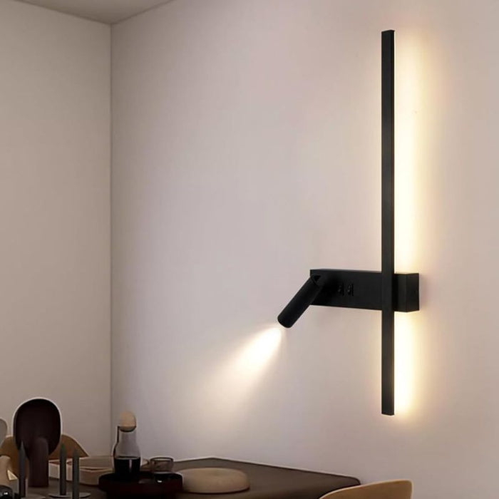 Modern wall-mounted light fixture on a neutral wall with a dining area in the background.