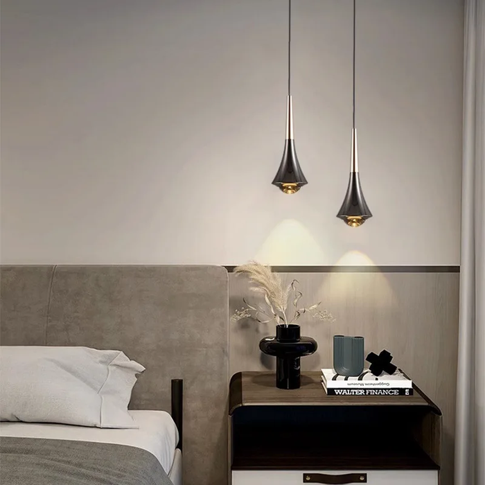 Modern bedroom with pendant lights, nightstand, and decorative items.