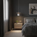 Modern bedroom with dark walls, a bed, nightstand, and pendant light.