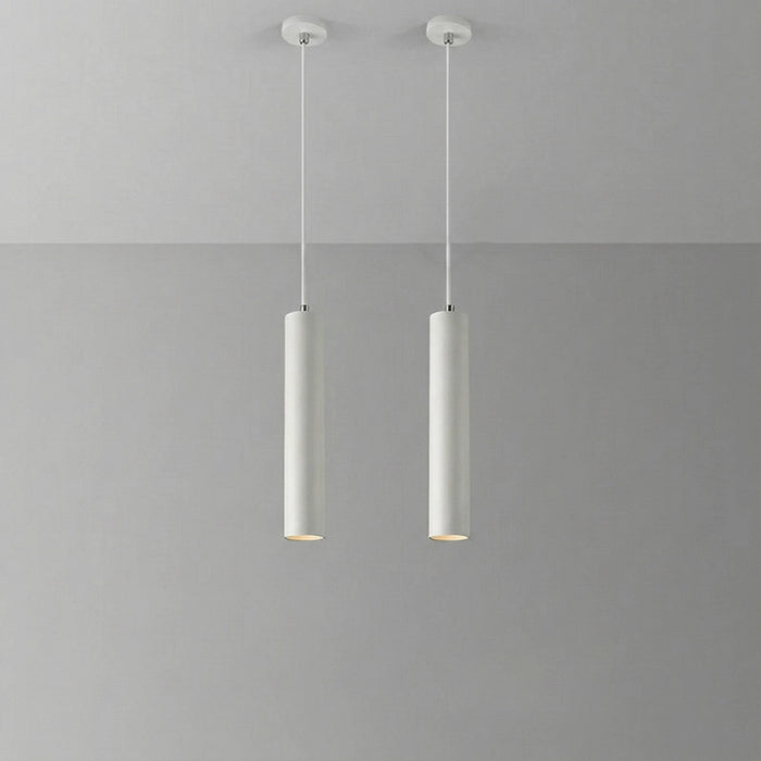 Two cylindrical pendant lights hanging against a gray background