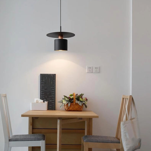 Small dining area with a table, chairs, and a hanging light fixture.