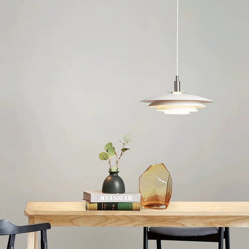 Pendant light fixture over a wooden table with decor items on a plain wall background