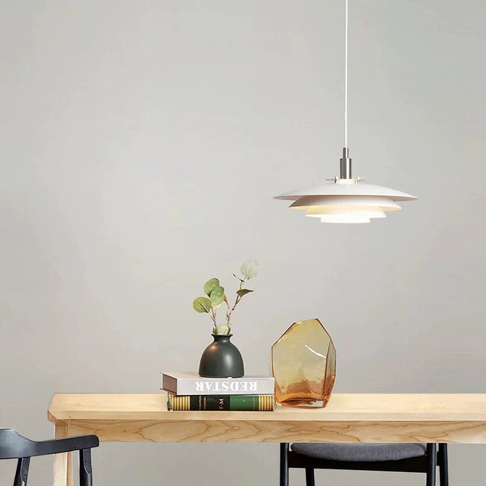 Pendant light fixture over a wooden table with decor items on a plain wall background