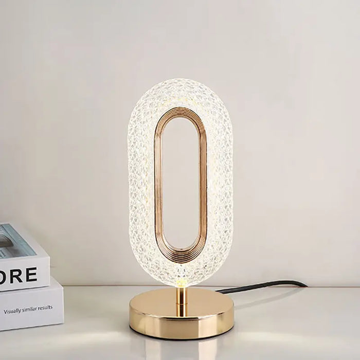 Modern table lamp with gold base and textured white shade on a neutral background