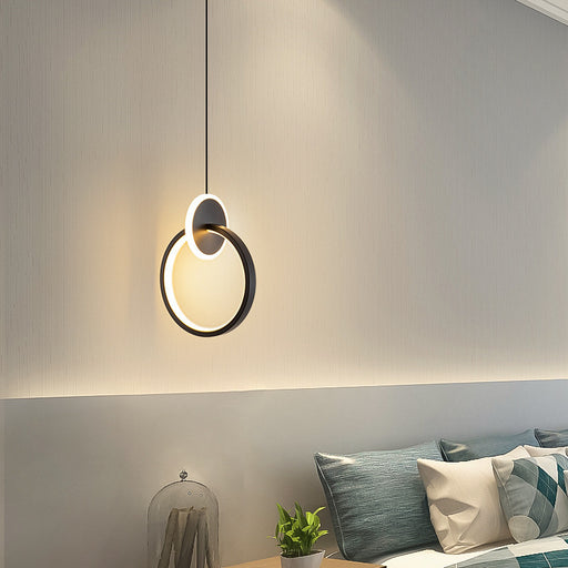 Modern pendant light fixture in a room with pillows and a plant.