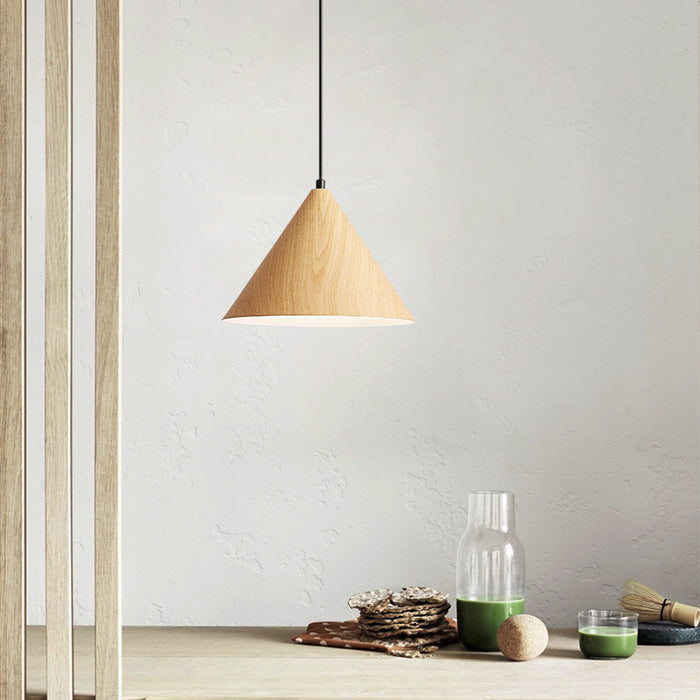 Wooden pendant lamp hanging above a table with decorative items on a light gray wall background.