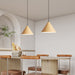 Modern kitchen with wooden pendant lights, table, and chairs.