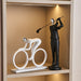 Decorative sculptures of a cyclist and a golfer on a shelf.