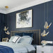 Modern bedroom with dark blue walls, gold headboard, and decorative lighting fixtures.