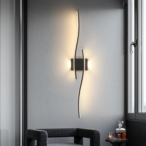 Modern wall sconce on a gray wall with a chair and small table in the foreground.