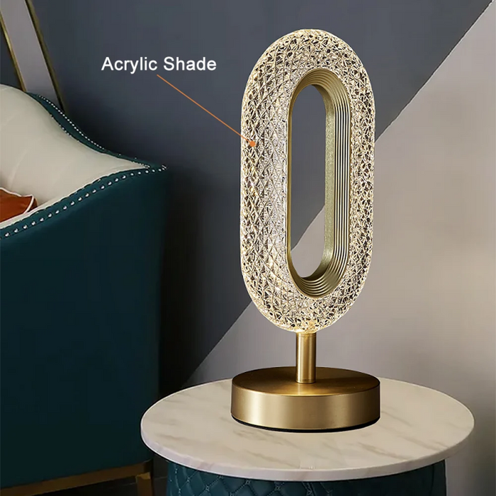 Decorative table lamp with gold base and textured acrylic shade on a marble surface.